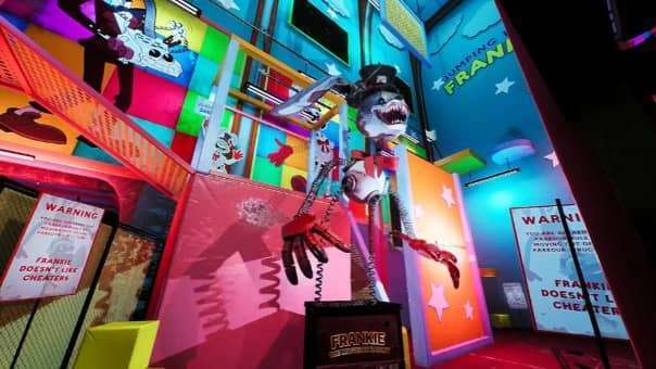 Finding Frankie review – statue of Frankie bursting from a jack-in-the-box, showcasing eerie amusement park horror design.