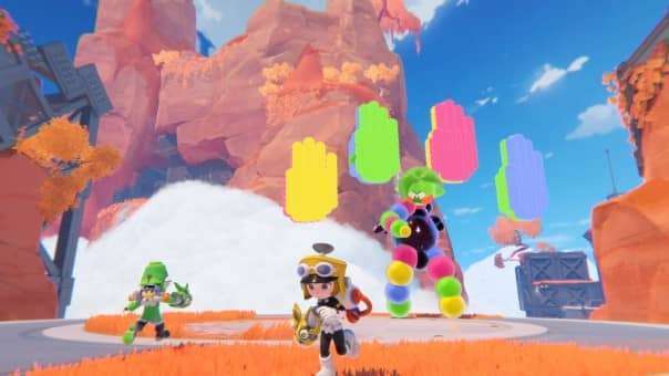 Two players fight a towering, multicolored boss in POPUCOM’s desert landscape, using teamwork to overcome the challenge.