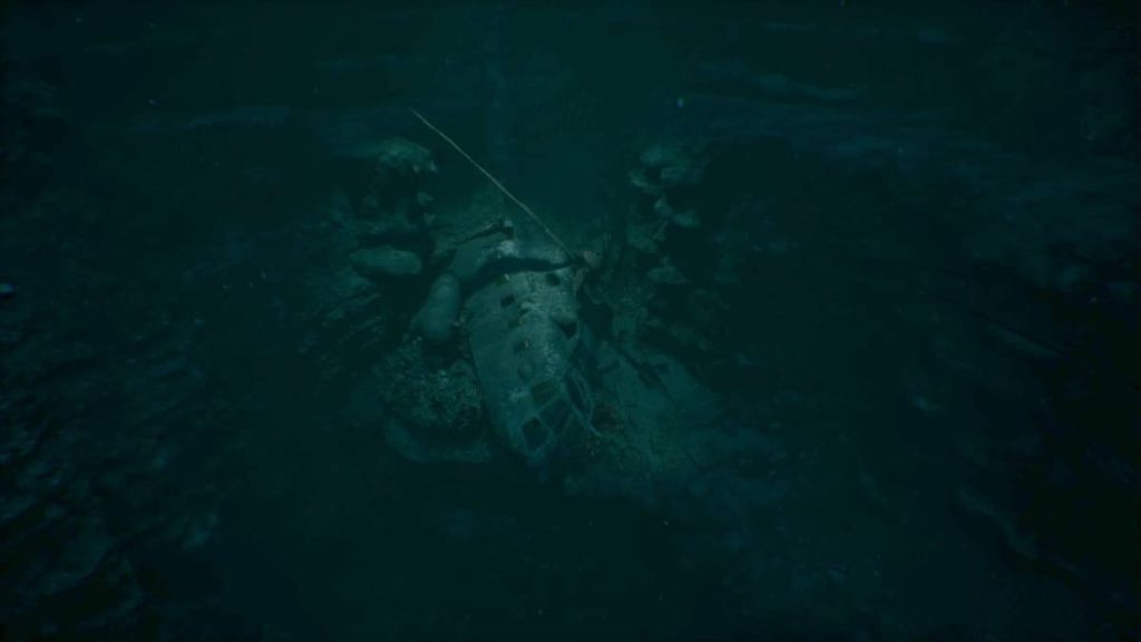 Wreckage of the base game’s helicopter lies sunken on the seabed in this review snapshot.