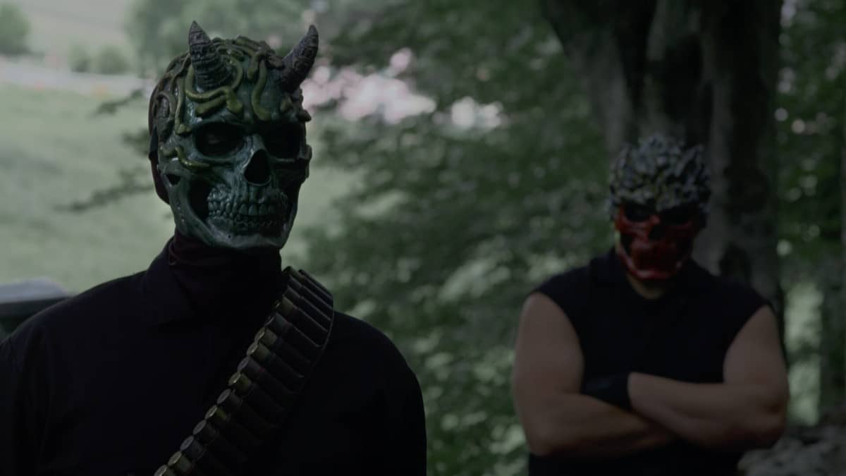 Two masked killers exchange a tense look in the forest in The Run as they plan their next move.