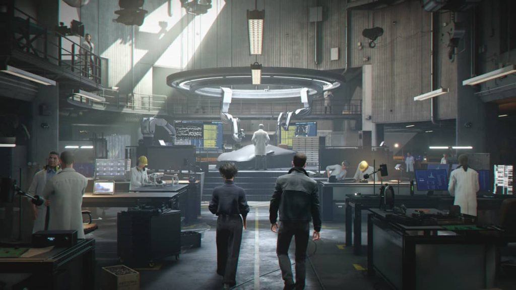 Bond visits Q branch where scientists develop gadgets around a covered car in 007 First Light.